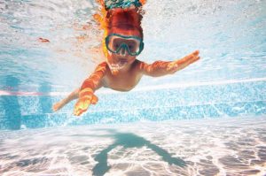 child in goggles swimming in pool